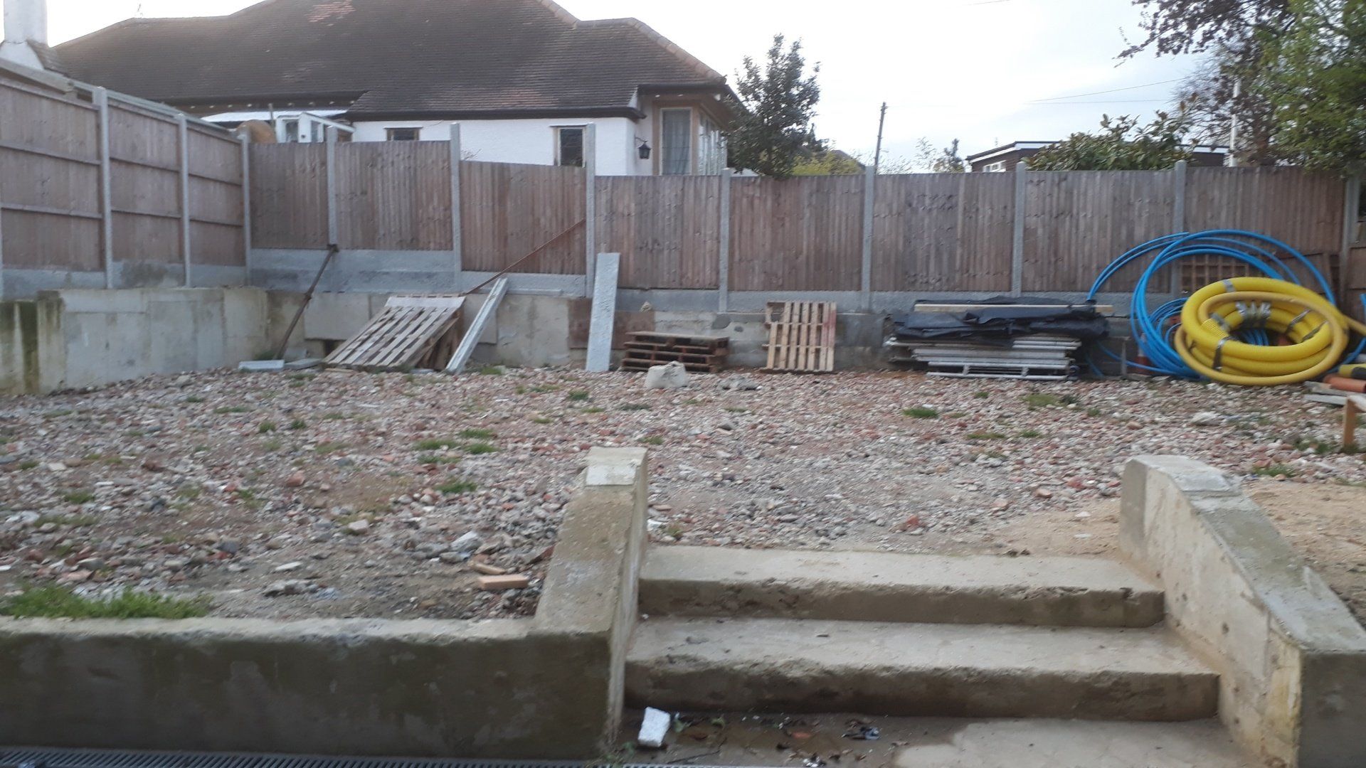 A backyard with a wooden fence and stairs leading to it.