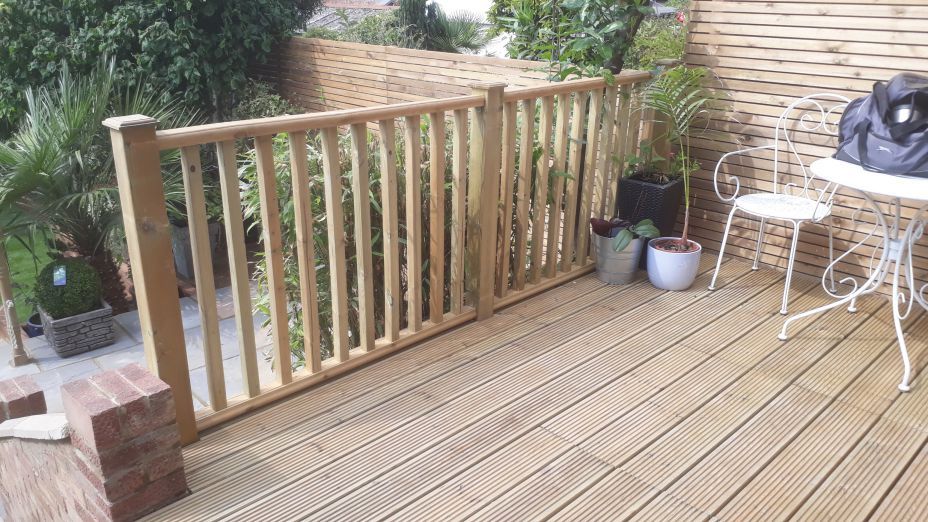 decking and railings A wooden deck with a table and chairs on it.
