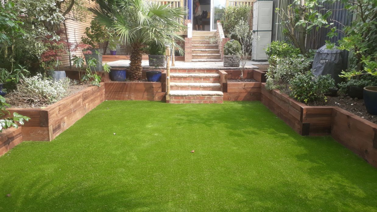 A backyard with a lush green lawn and stairs leading up to a house.