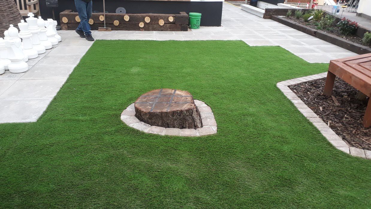 A stump in the middle of a lush green lawn.