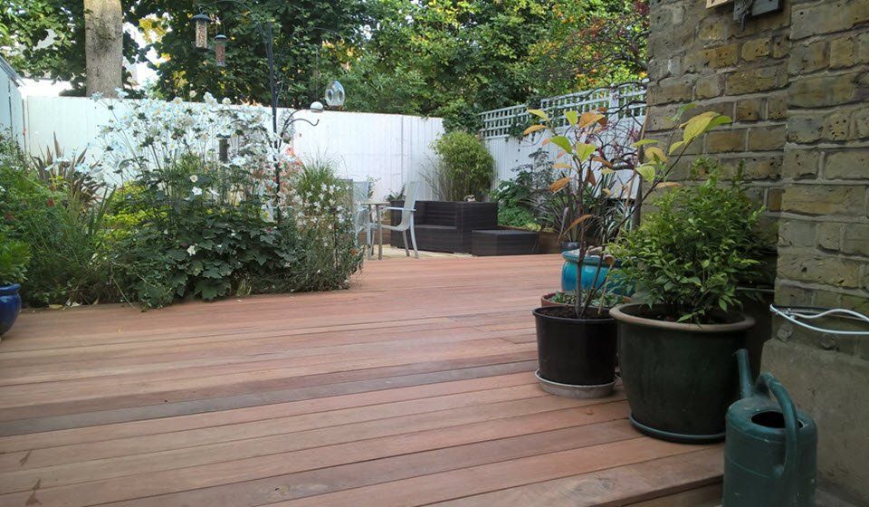 A wooden deck with potted plants and a watering can