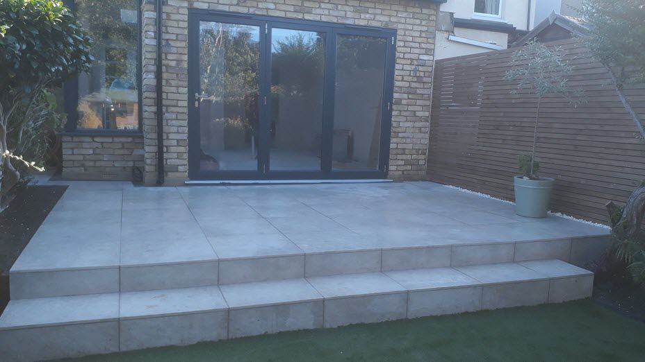 A patio with steps leading up to a brick building with sliding glass doors.