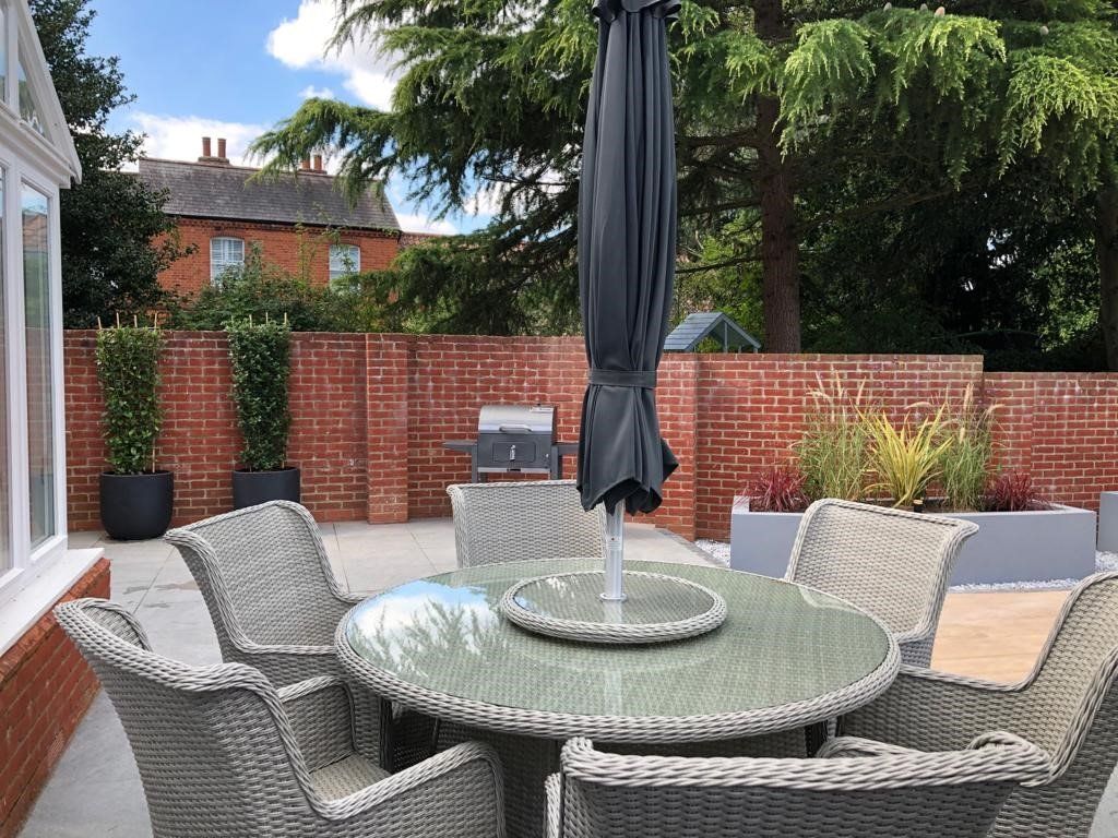 A patio with a table and chairs and an umbrella.