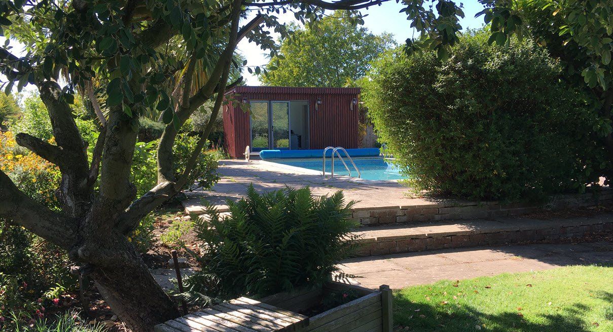 There is a swimming pool in the backyard of a house surrounded by trees.