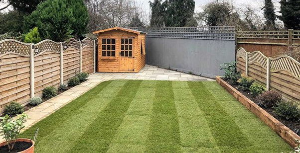 A backyard with a wooden shed and a lush green lawn.