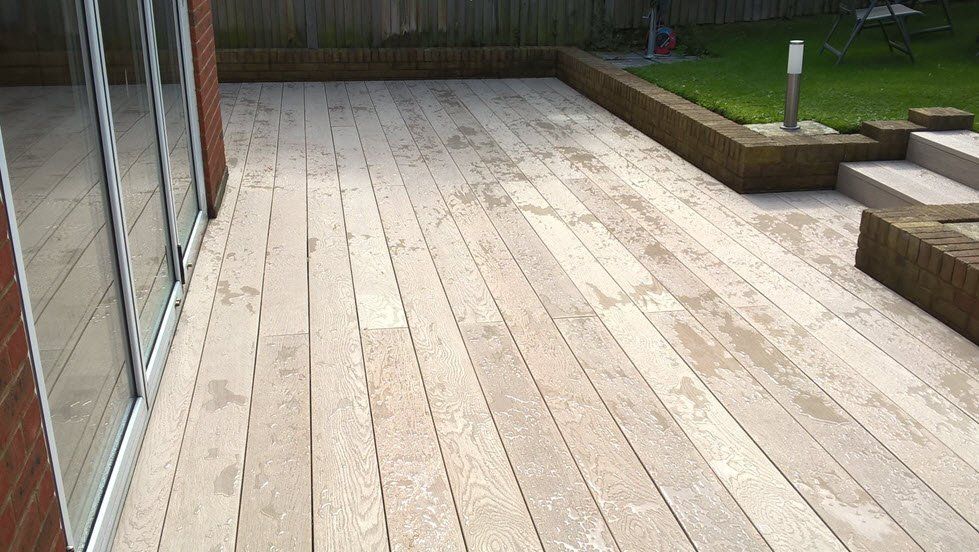 millboard-decking A wooden deck with sliding glass doors and stairs in a back garden