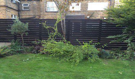 slatted fencing design There is a black fence in the backyard of a house.