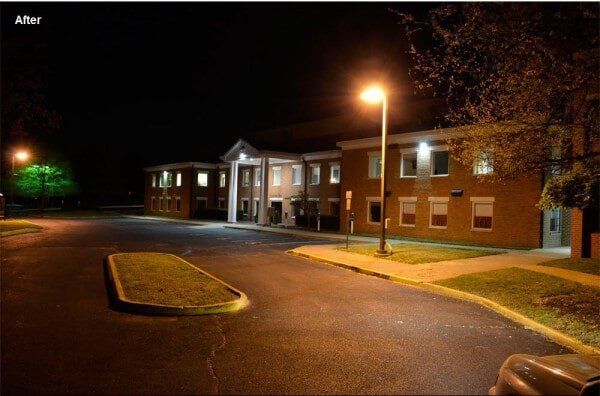 Nighttime shot of a two-story brick building with lights on, street lights illuminating the empty street.
