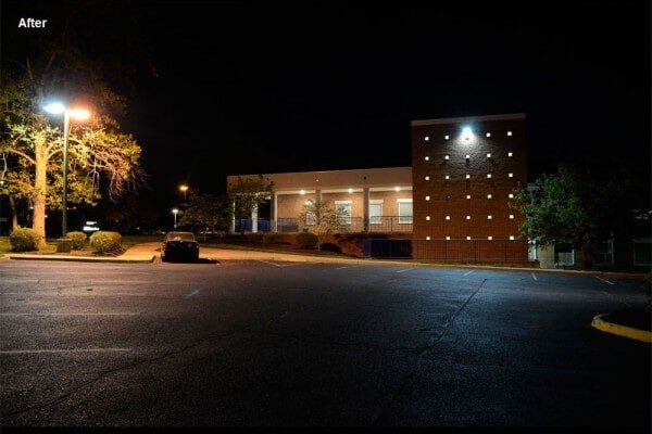 Nighttime parking lot with building and streetlights.