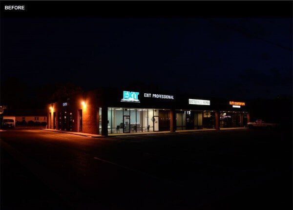 Nighttime view of a commercial building with glowing storefront signs and street lights illuminating the exterior.