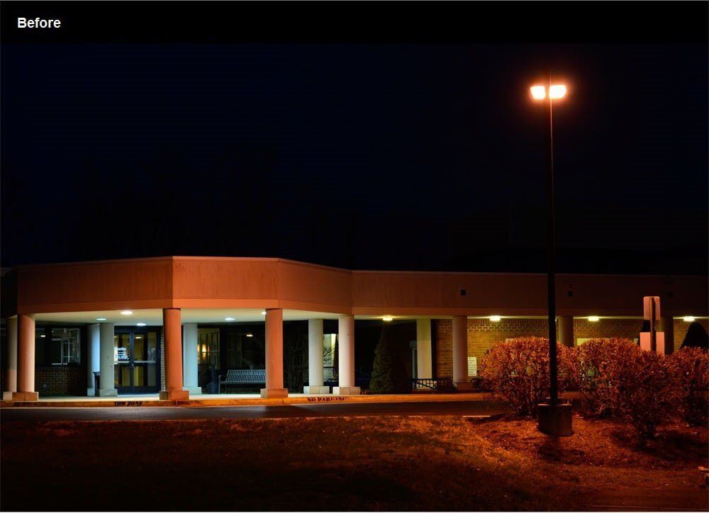 Building exterior lit at night, with columns and a street light.