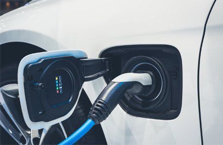 Charging Station — Car Charging in Fredericksburg, VA White electric car charging; blue charging cable inserted, open port.