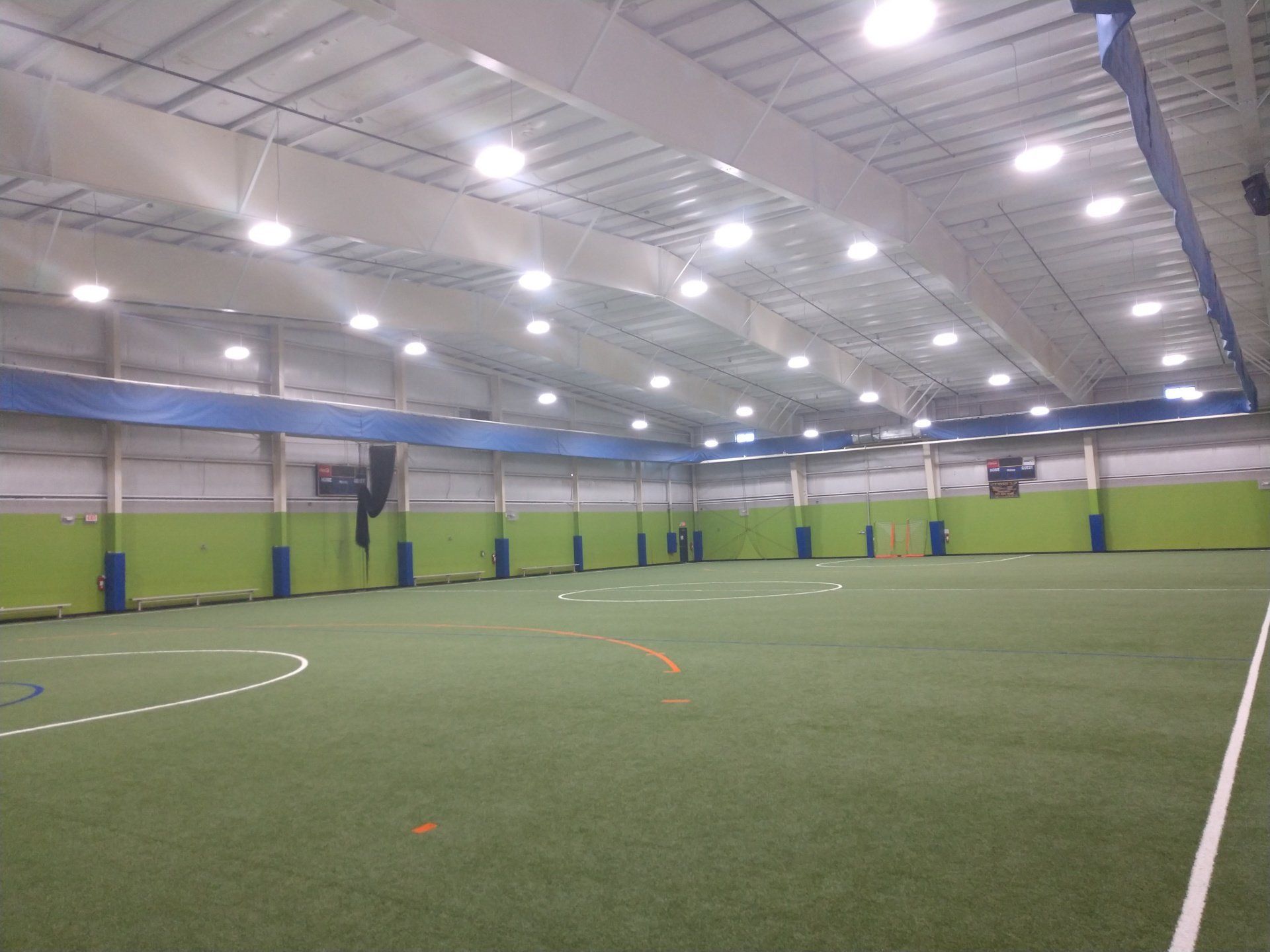 Indoor soccer field with green turf, white lines, and overhead lighting.