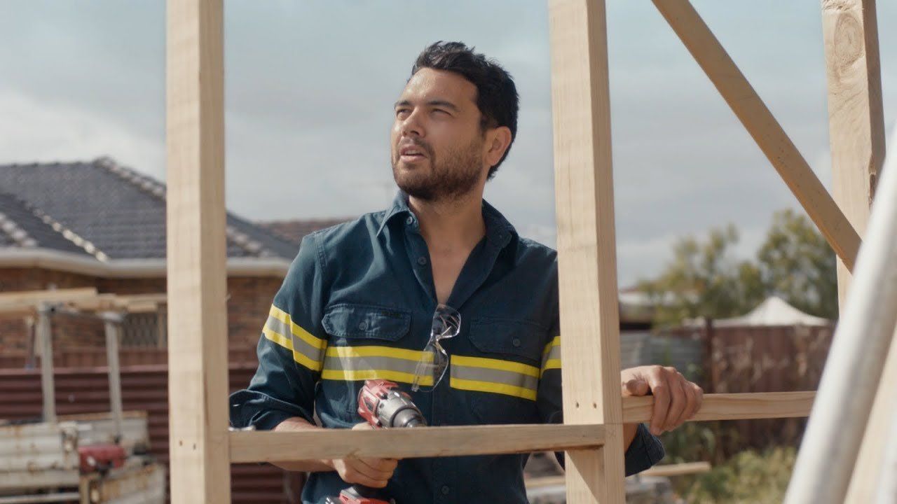 A worker building a house and looking at the sky