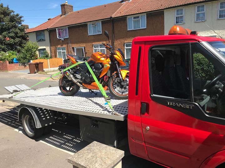 A.C Recovery's, 24 hour towing service in Barking and Dagenham, orange motorcycle being towed by red towing truck in broad daylight