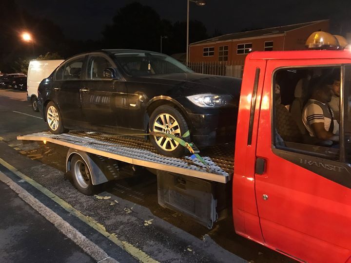 A.C Recovery's, 24 hour towing service in Barking and Dagenham, black car being towed by a red towing truck in the middle of the night