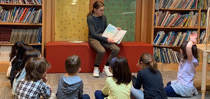 Adolescent 7th grade student reading to preschool aged children