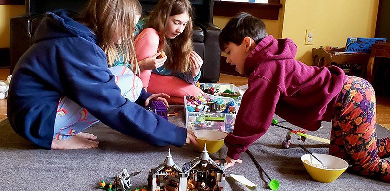 three children with lego playing on a carpet