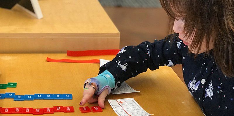 First grade elementary student doing addition with 100s tiles