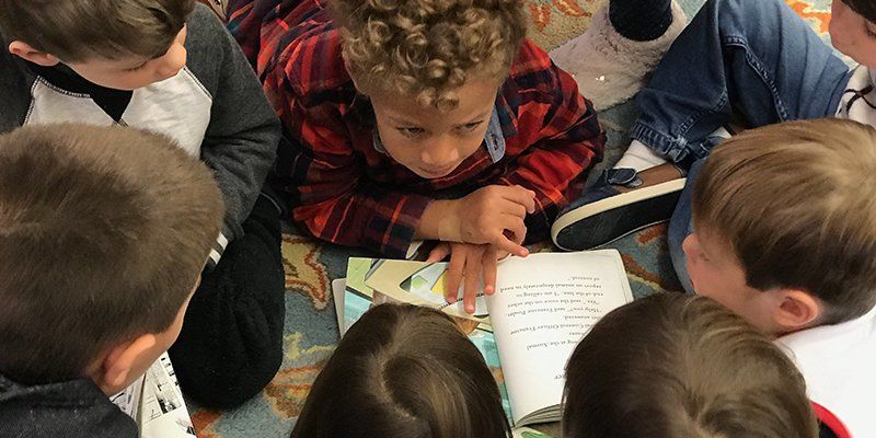 group of preschool aged children sitting on the floor, reading with each other