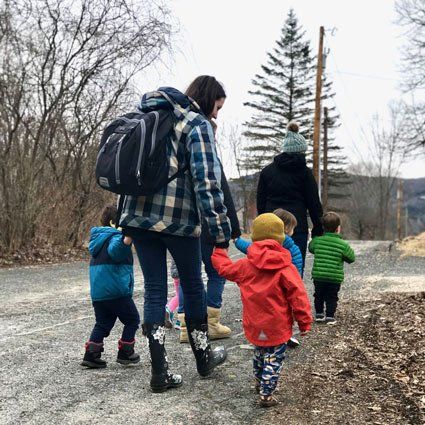 Toddlers walking outdoors with teachers