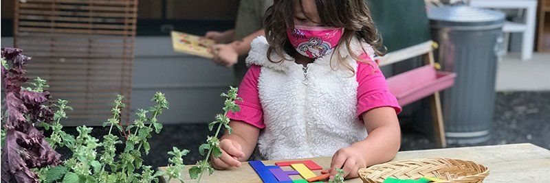 young child outdoors with lesson of colorful shapes