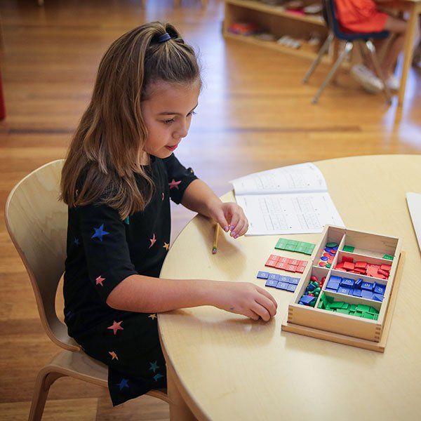 Elementary child seated at a small table with a lesson