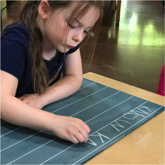 Child writing on chalkboard