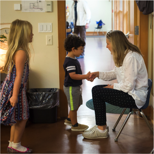 Standing child and seated adult shaking hands