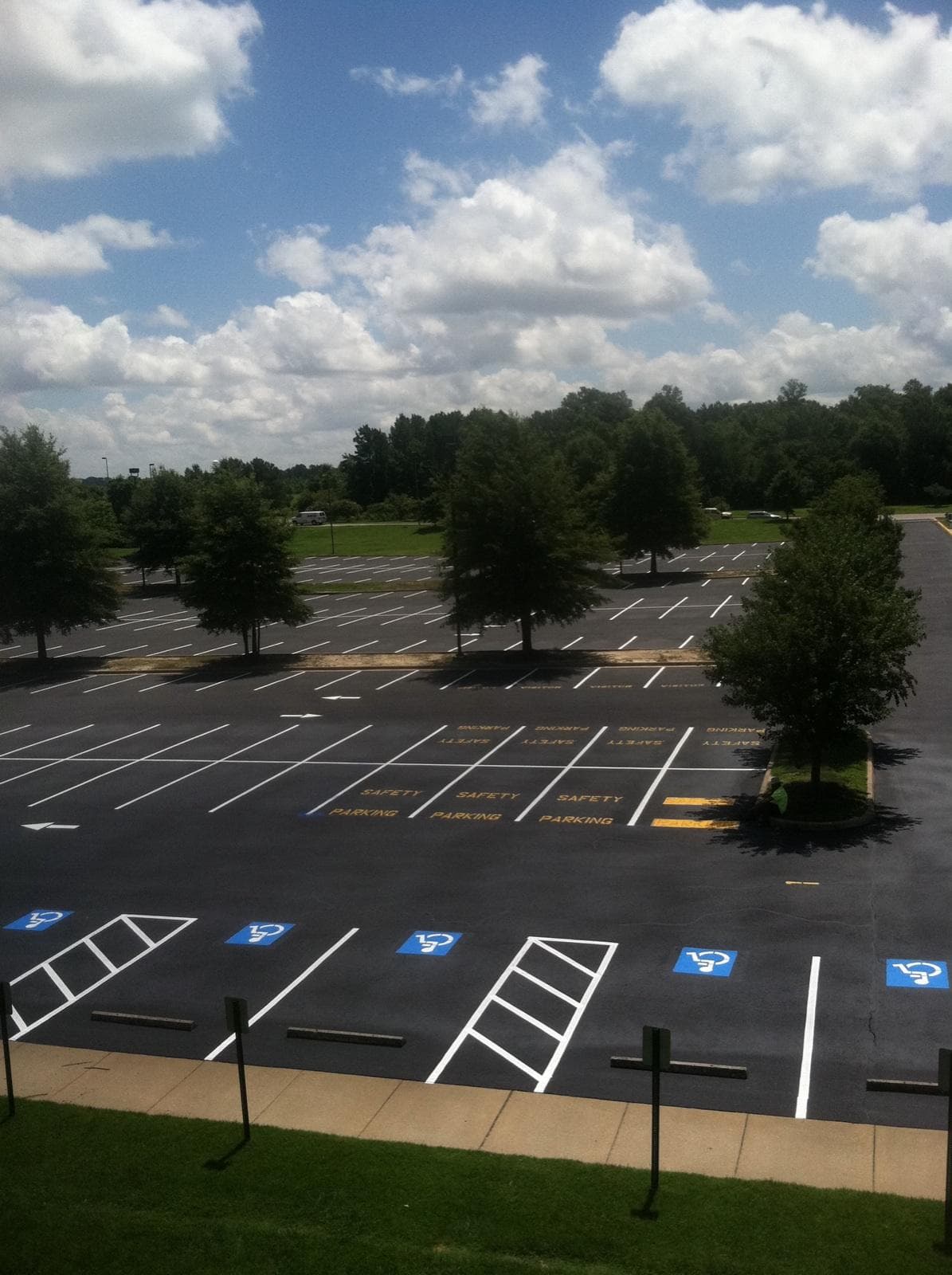 An empty outdoor parking lot with multiple clearly marked accessible parking spaces under a partly cloudy sky.
