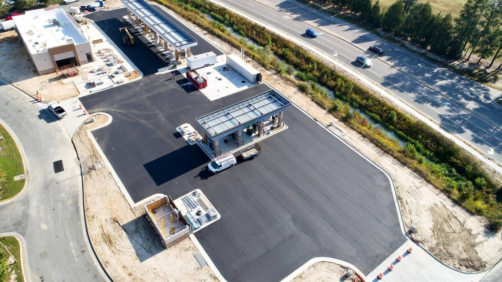 Aerial view of a gas station under construction with paved parking, fuel pump islands, and a main building.