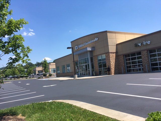 A beige commercial building with glass garage doors and a parking lot under a bright blue sky.