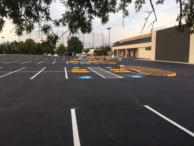 An empty parking lot with two blue-painted accessible parking spaces marked with wheelchair symbols.