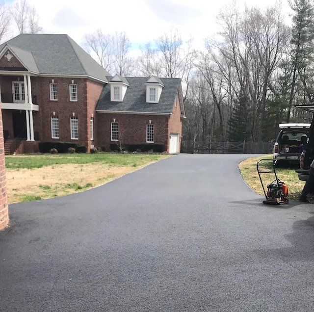 A driveway with a brick house in the background
