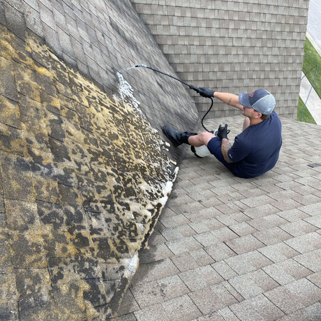 man power washing on roof