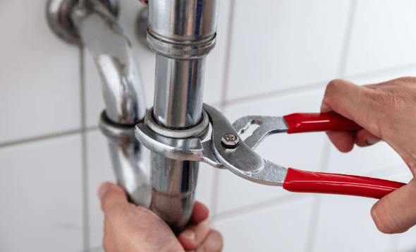 Hands doing plumbing work with wrench
