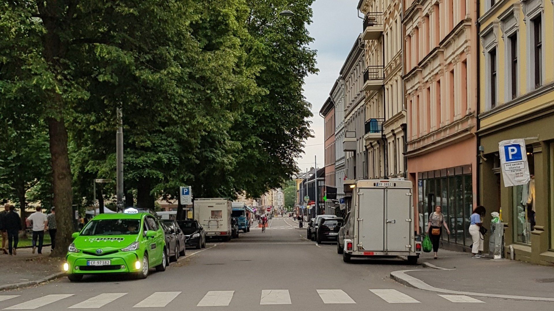 A green taxi is parked on the side of a city street.