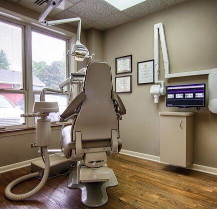 Dr's operatory - Sacrey & Sacrey Dentistry Geneva, IL Dentist's office with dental chair, equipment, cabinets, a window, and wood flooring.