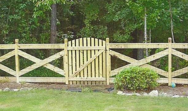 Pale yellow wooden fence with a centered gate and diagonal cross-bracing along a grassy yard edge.