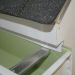 Dripedgeextension A close-up view of a green gutter installed below a white fascia board and gray roof shingles.