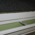 Dripedgeextension2 A close-up view of a white, disassembled baseboard heater showing internal green panels and metal mounting brackets.