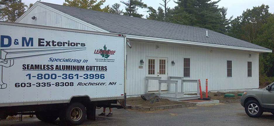 D&M Exteriors truck parked in front of a white building with an accessible ramp leading to the entrance.