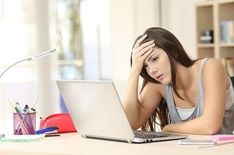 Worried and sad student female searching information in a laptop on line in a desk at home room