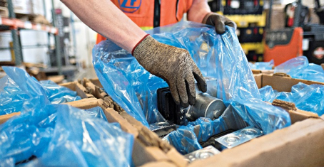 A man is wrapping a piece of metal in a plastic bag.