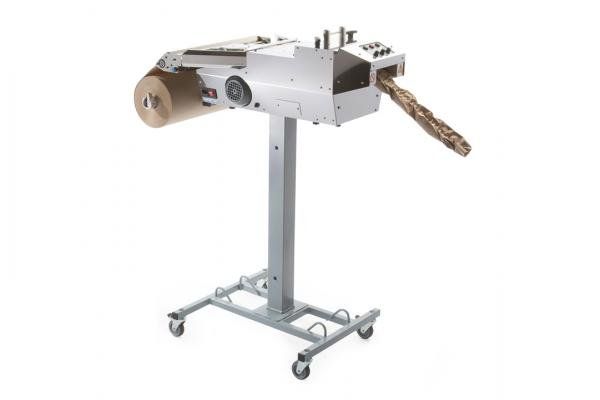 A machine is sitting on a stand with a roll of brown paper coming out of it.