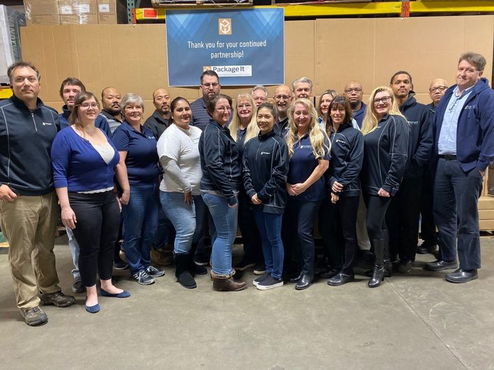 A group of people are posing for a picture in a warehouse.
