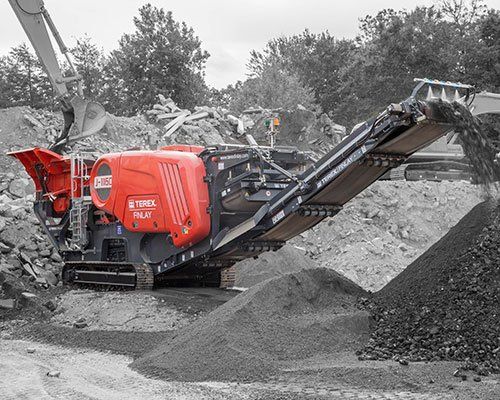 Una máquina roja y negra está sentada encima de una pila de rocas.