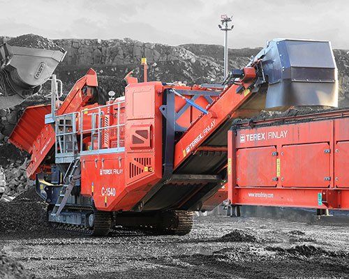 Una gran máquina roja está sentada encima de un campo de tierra.