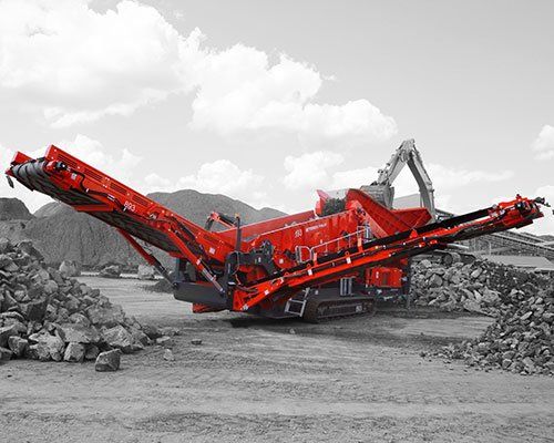 Una gran máquina roja está sentada encima de una pila de rocas.