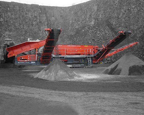 Una gran máquina se encuentra encima de un montón de tierra en un campo.
